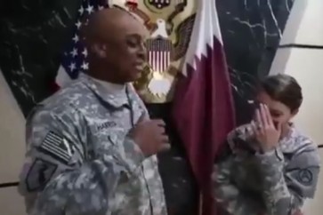 مجنداومجندة أمريكيين يضحكان قبالة علمين للولايات المتحدة وقطر