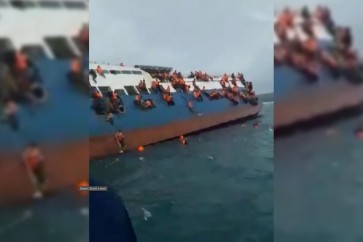 ركاب عبارة إندونيسية يتشبثون بها أثناء غرقها