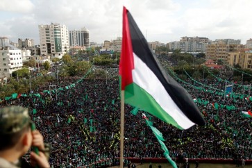 العلم الفلسطيني فوق أنصار حركة حماس في مسيرة بمناسبة الذكرى الثلاثين لتأسيس الحركة، في قطاع غزة بفلسطين